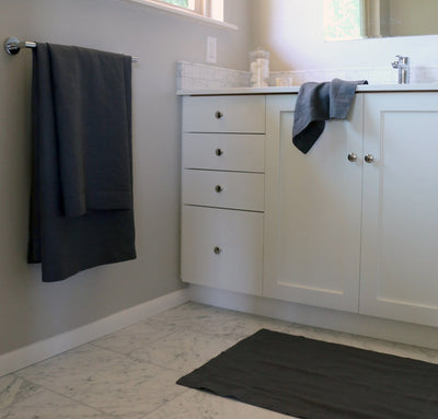 bathroom scene with 100% linen bathroom linens including bath sheet bath towel hand towel bath mat wash cloths heavyweight Orkney linen fabric charcoal dark grey color