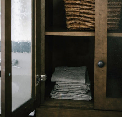 bathroom cabinet with folded stack of 100% linen bathroom linens including bath sheet bath towel hand towel bath mat wash cloths heavyweight Orkney linen fabric off-white white color