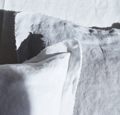 closeup detail of 100% linen pillow slip cover with raw edge detail pure white light grey colors