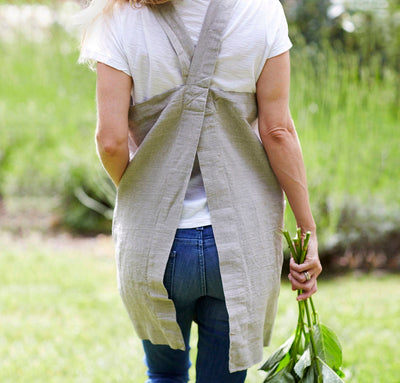 back detail of woman wearing 100% linen pinafore apron wrap design heavyweight Orkney linen fabric with pockets natural light brown tan beige color