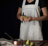 front detail of woman wearing 100% linen pinafore apron wrap design heavyweight Orkney linen fabric with pockets off-white color