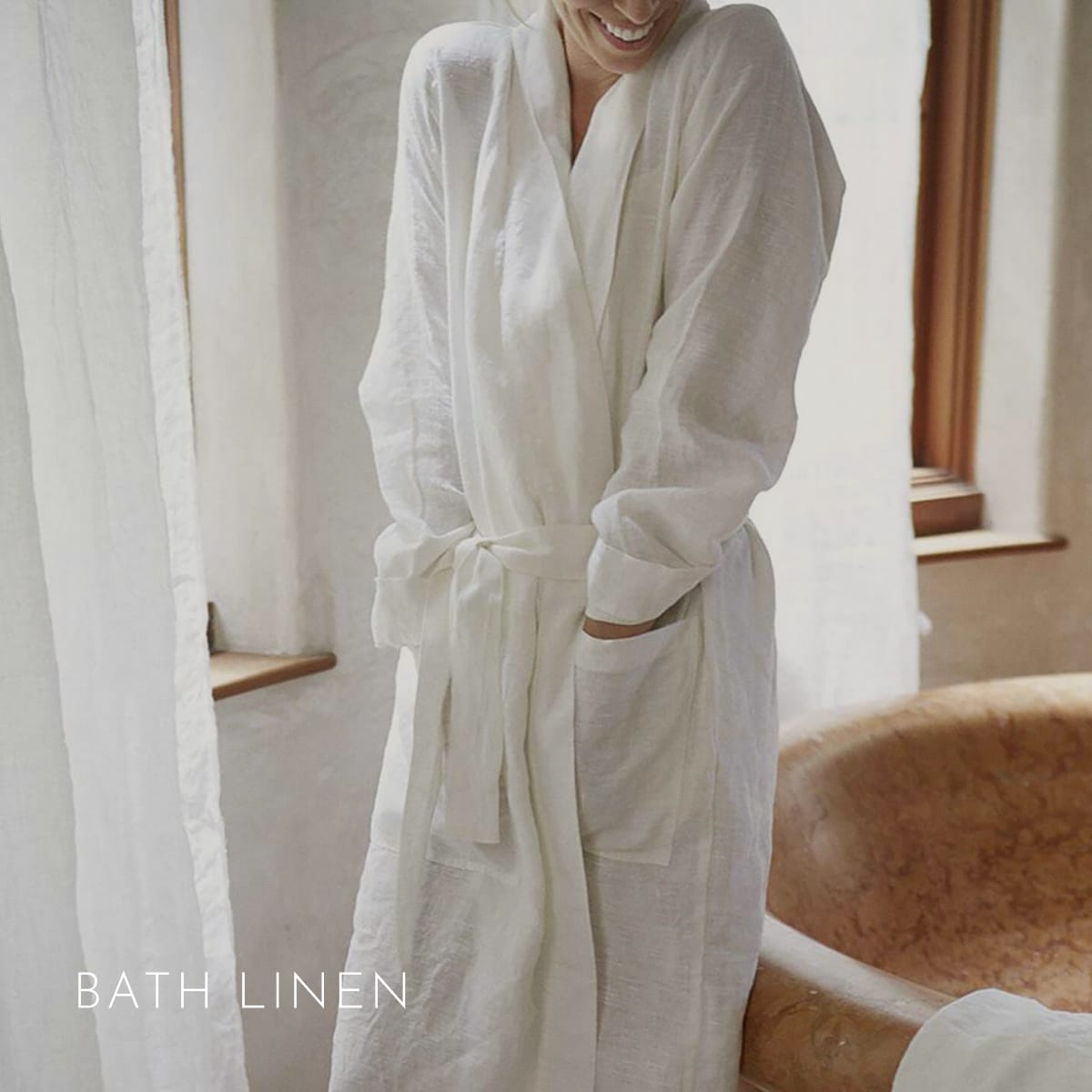 Woman in an off-white St. Barts linen robe by a copper tub — Bath Linen