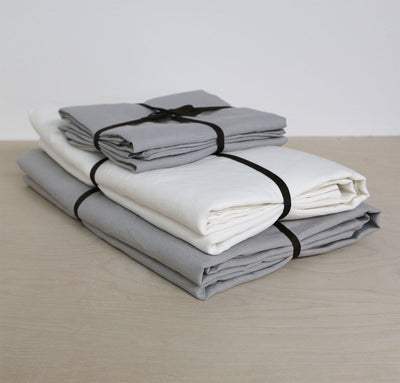 folded stack of 100% linen summer bed set including bottom sheet pillow cases summer cover blanket light grey pure white colors