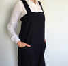front detail of woman wearing 100% linen pinafore apron wrap design heavyweight Orkney linen fabric with pockets black color