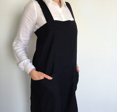 front detail of woman wearing 100% linen pinafore apron wrap design heavyweight Orkney linen fabric with pockets black color