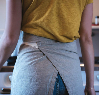 back detail of woman wearing 100% linen apron heavyweight Orkney linen fabric natural light brown beige tan color