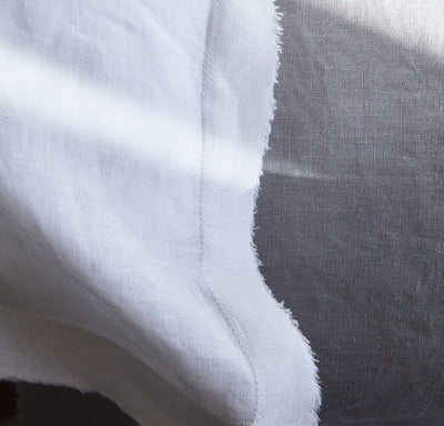 closeup detail of 100% linen pillow slip cover with raw edge detail pure white