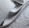 closeup detail of 100% linen summer cover blanket with frayed raw edge detail light grey color