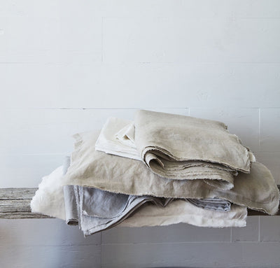 stack of 100% linen summer cover blankets with frayed raw edge detail natural beige light tan light grey pure white colors