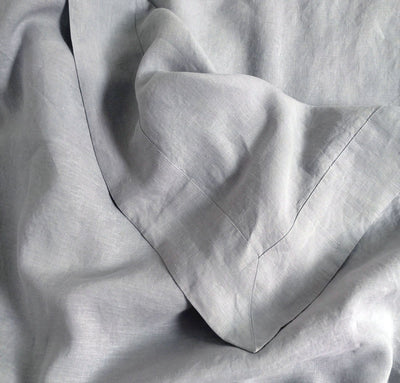 closeup detail of 100% linen summer bed set including bottom sheet pillow cases summer cover blanket light grey color
